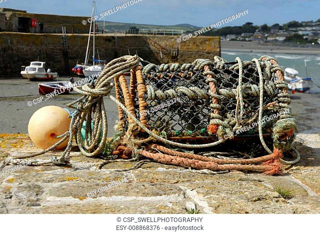 One empty lobster pot on harbour wall