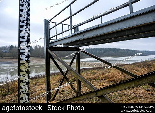 PRODUCTION - 15 December 2023, Bavaria, Stadtlauringen: A jetty and a level gauge are on dry land. All the water had to be drained from Lake Ellertshausen at...