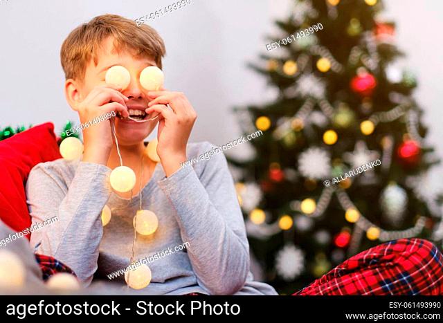 Portrait of a Christmas boy. A cute smiling child is having fun making a funny face with Christmas balls on his eyes
