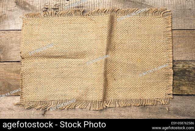 brown burlap fragment on gray wooden background, top view