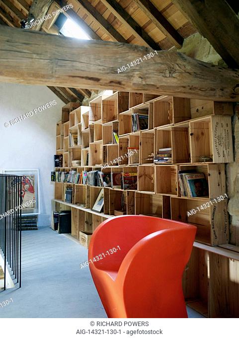 Stacked wooden wine crate storage in interior wooden beamed roof space with artwork, books and vinyl in residential house, France