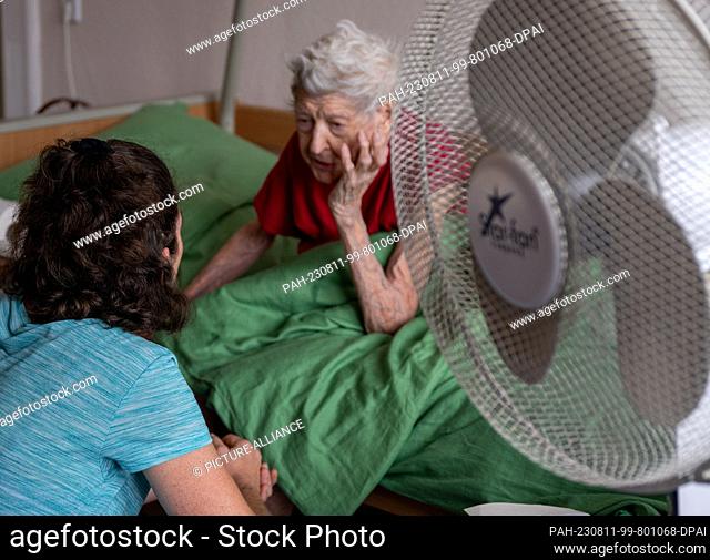 PRODUCTION - 31 July 2023, Berlin: Nurse Ramona Rössner talks to her patient, 97-year-old senior Brigitte Richter, who is in need of care, during a home visit
