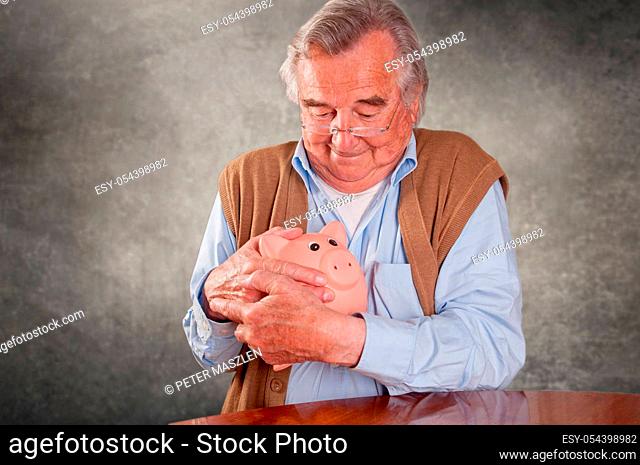 Portrait of senior man keeping his piggy bank save