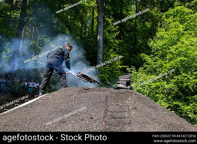 27 May 2023, Saxony, Tharandt: A charcoal pile is lit in the Breiten Grund in the Tharandt forest by members of the Meiler Tharandt e.V