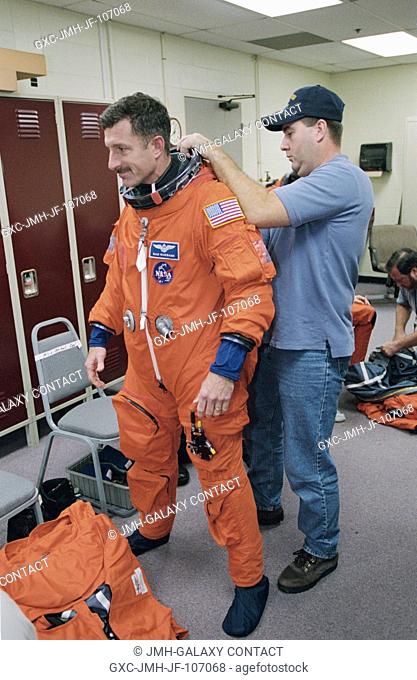 Astronaut Daniel C. Burbank, STS-115 mission specialist, dons a training version of the shuttle launch and entry suit prior to the start of an emergency egress...