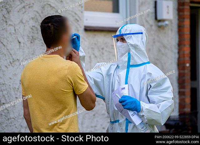 22 June 2020, North Rhine-Westphalia, Rheda-Wiedenbrück: A helper from the German Red Cross (DRK) takes a smear test on a man in front of a house