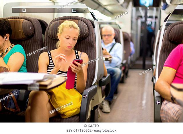 Thoughtful young lady surfing online on smartphone while traveling by train