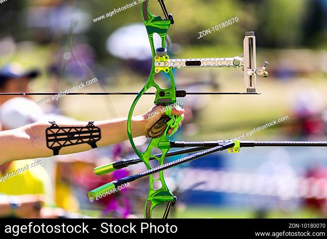 Person is shooting with recurve bow during an archery competition. Hand and bow only. Green bow
