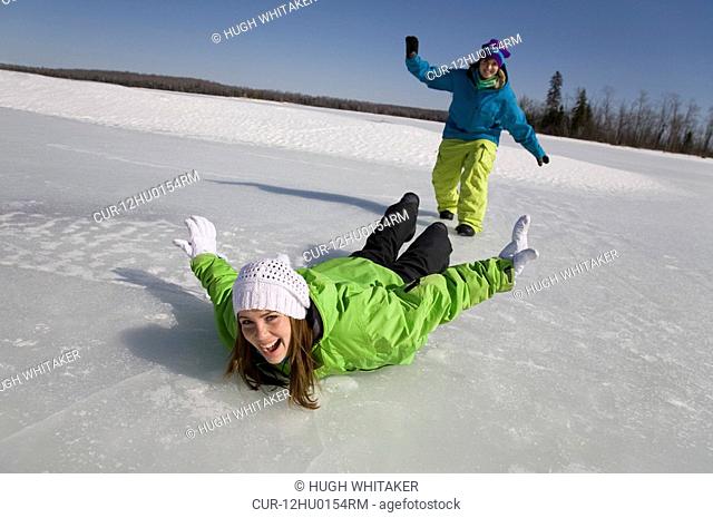 Two Women Sliding on Frozen Lake