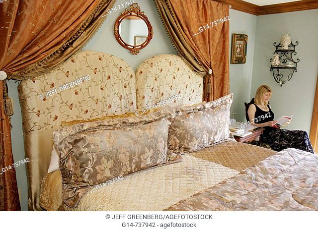 Arkansas, Eureka Springs, Angel at Rose Hall Bed and Breakfast Inn, guest bedroom, bed, Victorian style, woman, relax, read, flower print, bedspread, romantic