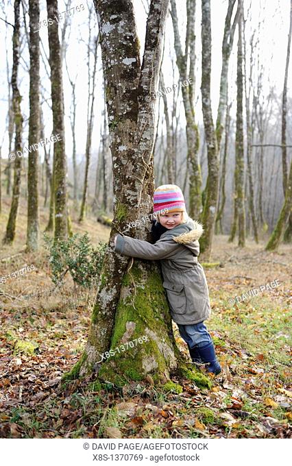 Five year old girl hugging a tree