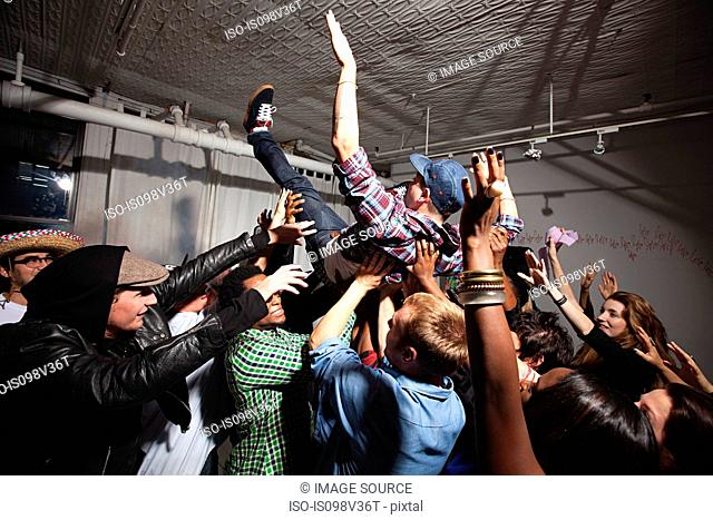 Man crowd surfing at party
