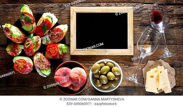 Wine and traditional Italian and American snacks. Salami, cheese, olives, brusquets, microgrin wooden background