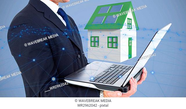 Midsection of businessman holding laptop against 3d house