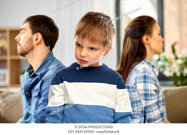 sad little boy with unhappy parents at home