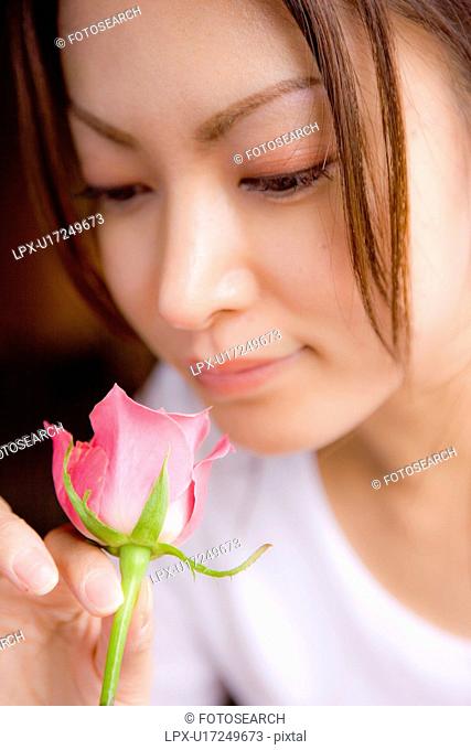 Young woman holding pink rose, close up