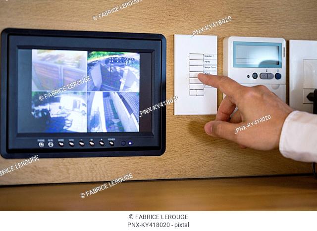 Person's hand pushing buttons for a security surveillance system at home