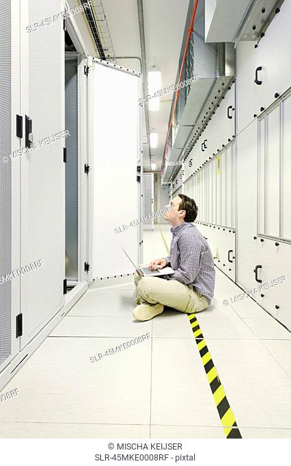 Businessman using laptop in server room