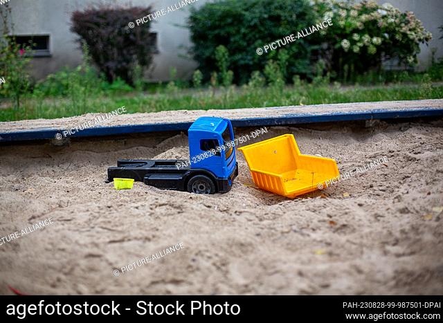 SYMBOL - 25 August 2023, Berlin: Some old and broken plastic toys are lying in the sand of a playground located near social housing