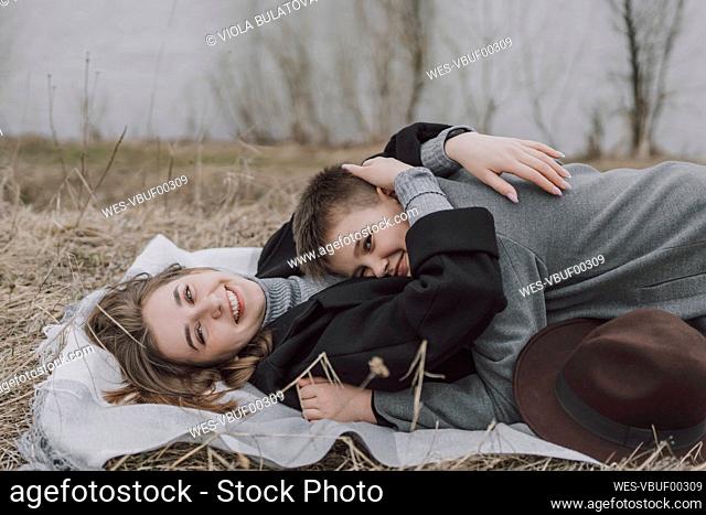 Smiling mother embracing son lying on grassy field