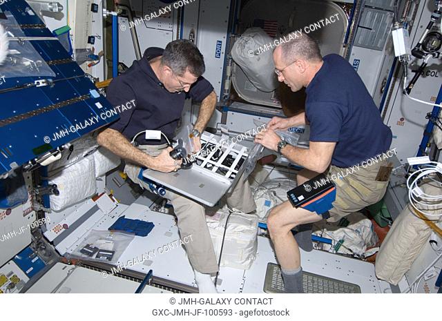 NASA astronauts Dan Burbank (left), Expedition 30 commander; and Don Pettit, flight engineer, stow camera equipment in a container in the Harmony node of the...