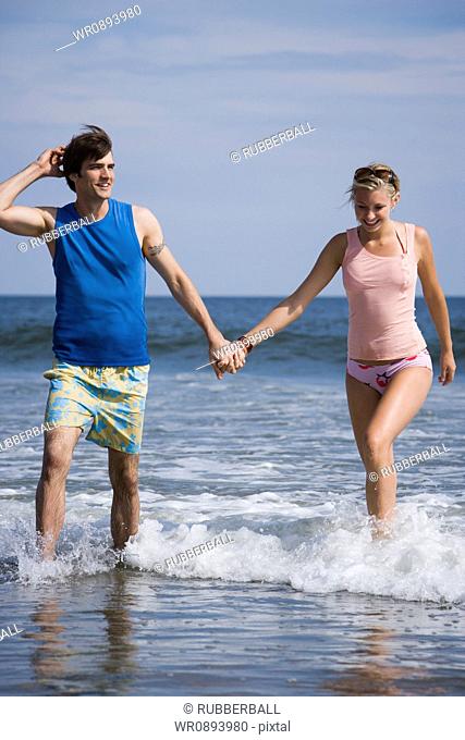 Young couple walking in the water on the beach