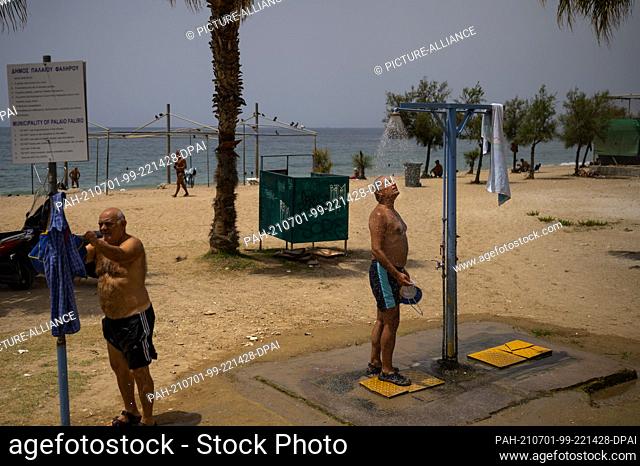 01 July 2021, Greece, Athen: A man showers during a heat wave on the beach in the suburb of Faliro. Temperatures are expected to reach 44 degrees Celsius in...