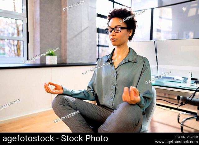 Young African Woman Sitting On Desk Meditating In Office