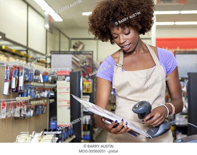 Portrait of an African American female store clerk standing at checkout counter scanning item