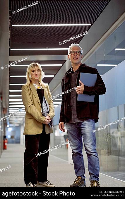 Businessman and businesswoman standing at corridor