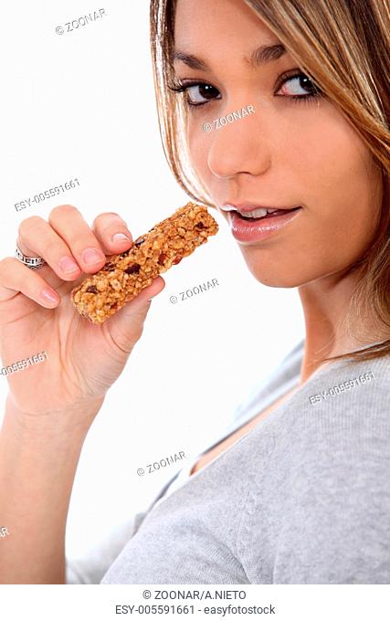 young woman eating a nut bar