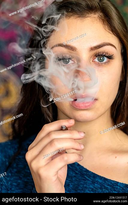A beautiful brunette model smokes marijuana in the privacy of her own home