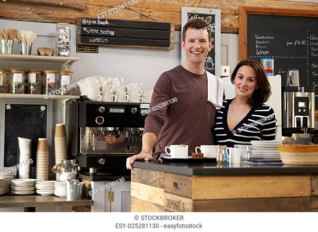 Smiling business owners behind the counter of their cafe