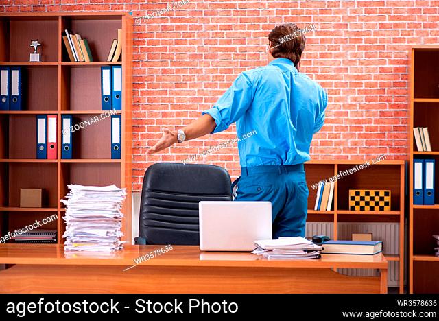 Young employee with excessive work sitting at the office