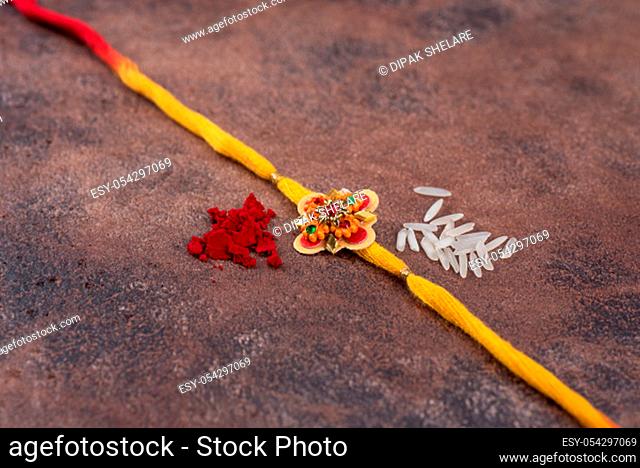 Raksha Bandhan : Rakhi with rice grains and kumkum on stone background, Traditional Indian wrist band which is a symbol of love between Brothers and Sisters