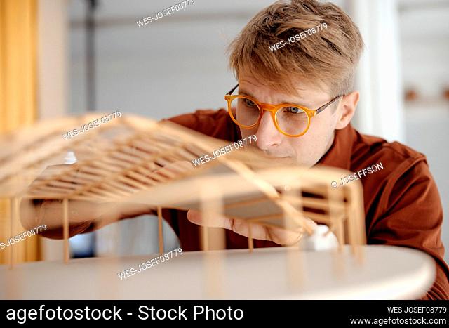 Architect wearing eyeglasses examining leaf shaped model at office