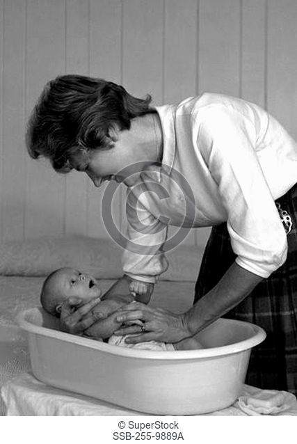 Young woman bathing newborn baby