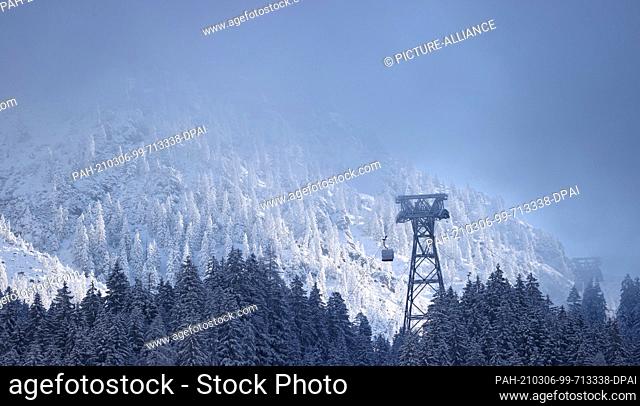 06 March 2021, Bavaria, Oberstdorf: A support of the new Nebelhorn cable car protrudes between the trees. The Nebelhornbahn has been renewed
