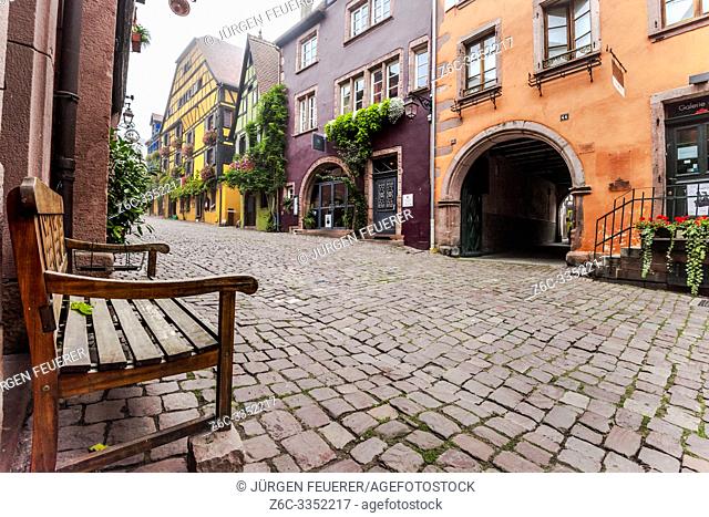 lane of the tourist destination Riquewihr, village of the Alsace Wine Route, France, cobblestone alley with vine and flower decoration