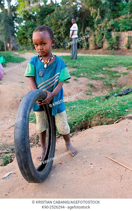 Africa, Ethiopia, Southern Ethopia, Jinka, Little boy standing on the street and holding a tire he is playing with