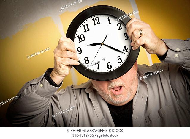 Middle-age balding man holding a clock