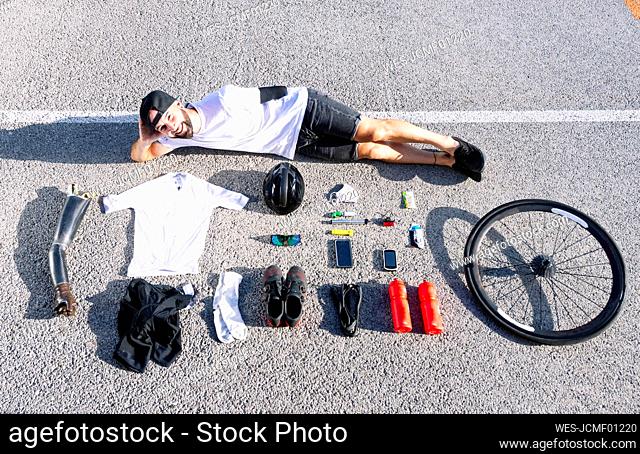 Smiling male adaptive athlete with various objects lying on road