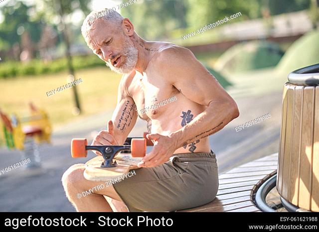 Leisure. A man sitting and fixing details of his skateboard