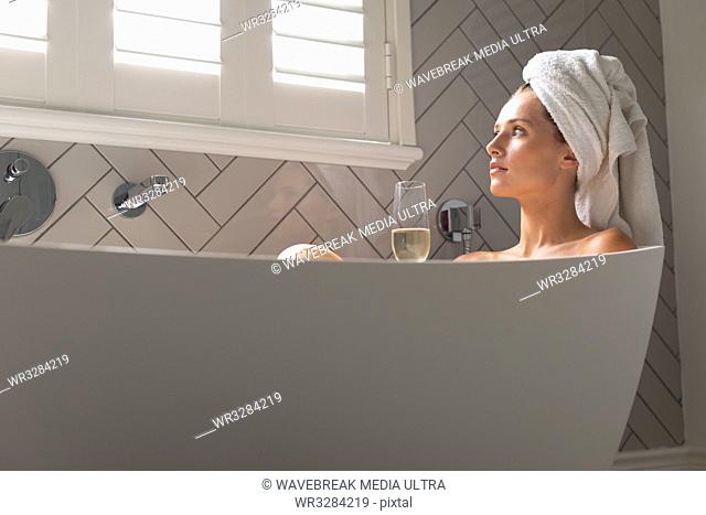 Thoughtful woman sitting in the bathtub in bathroom at home