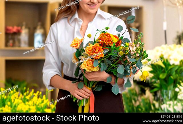 close up of happy woman with bunch at flower shop