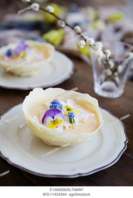 White chocolate bowl filled with mango mousse topped with coconut flakes