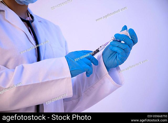 A doctor filling a syringe from the bottle for vaccination