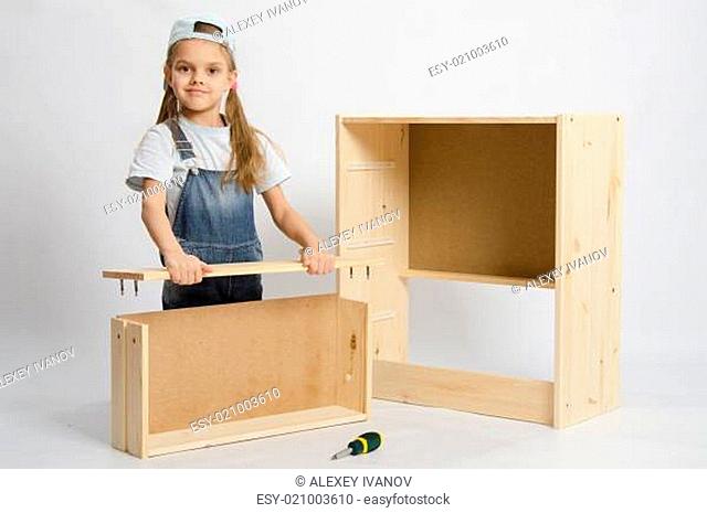 Six year old girl playing and collecting wooden cabinet