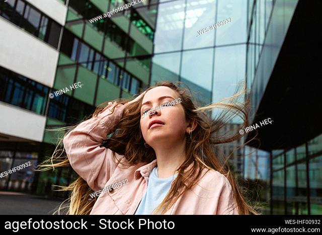 Young woman with eyes closed standing in front of building