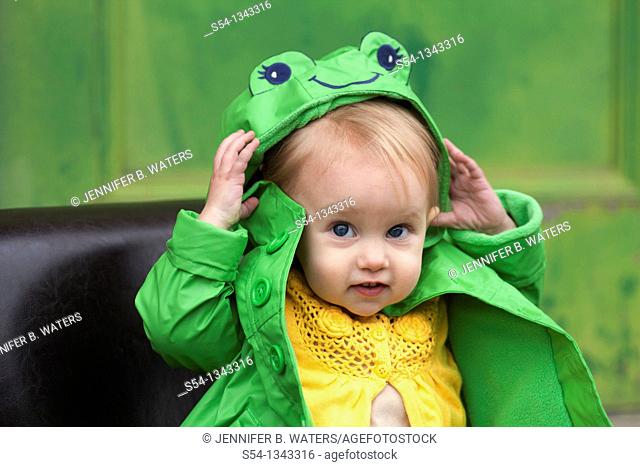 A toddler outdoors in a bright green raincoat
